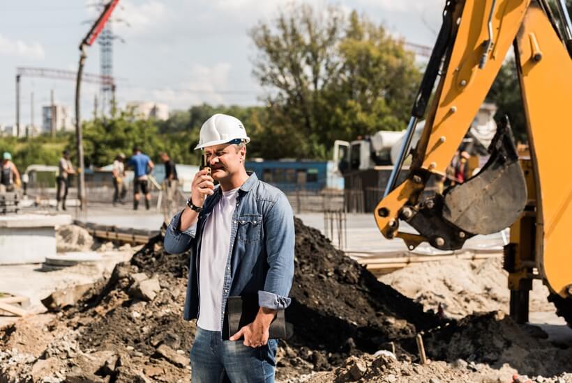 Engineer holding an walkie talkie on a construction site.